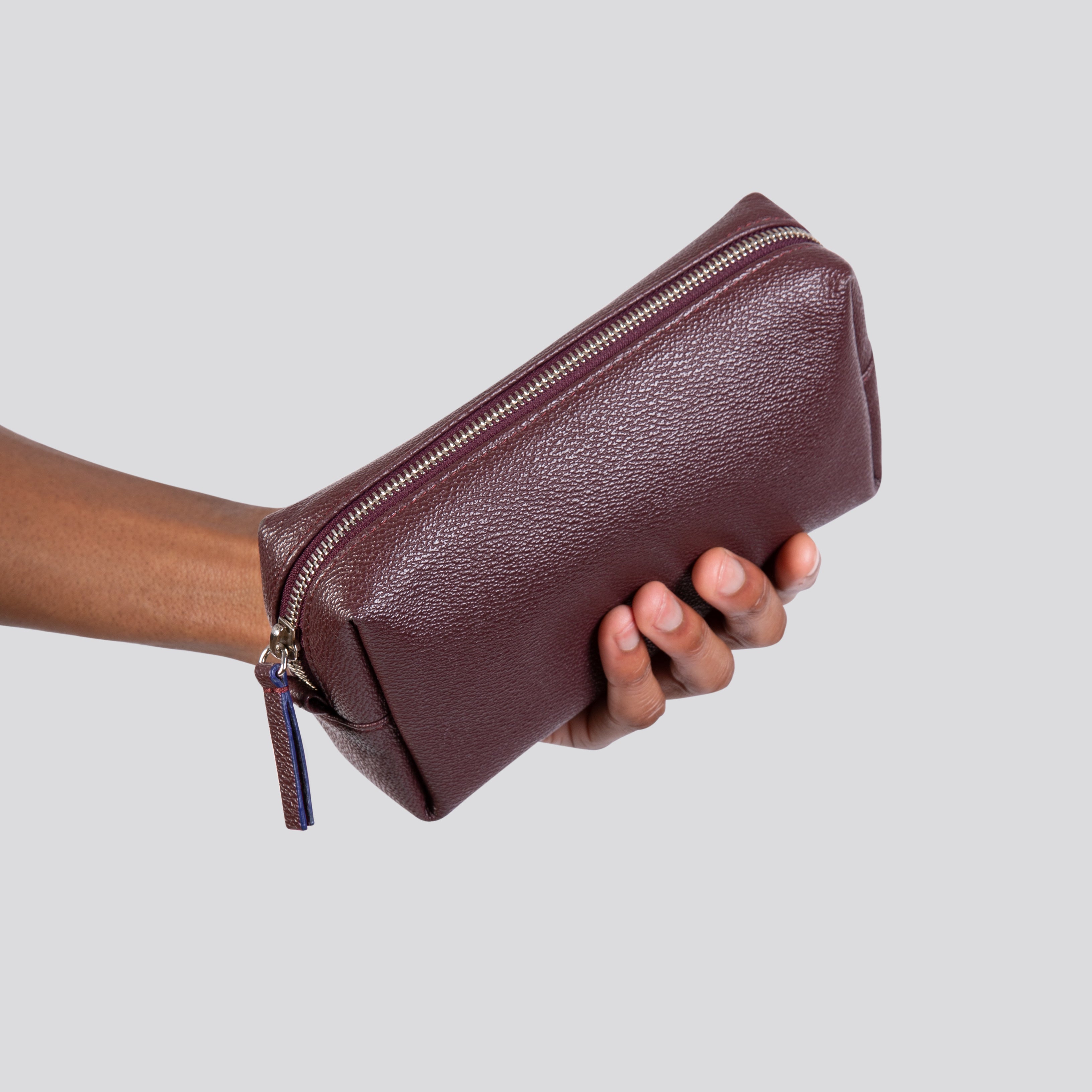 LUXTRA vegan toiletries bag, burgundy, held in hand