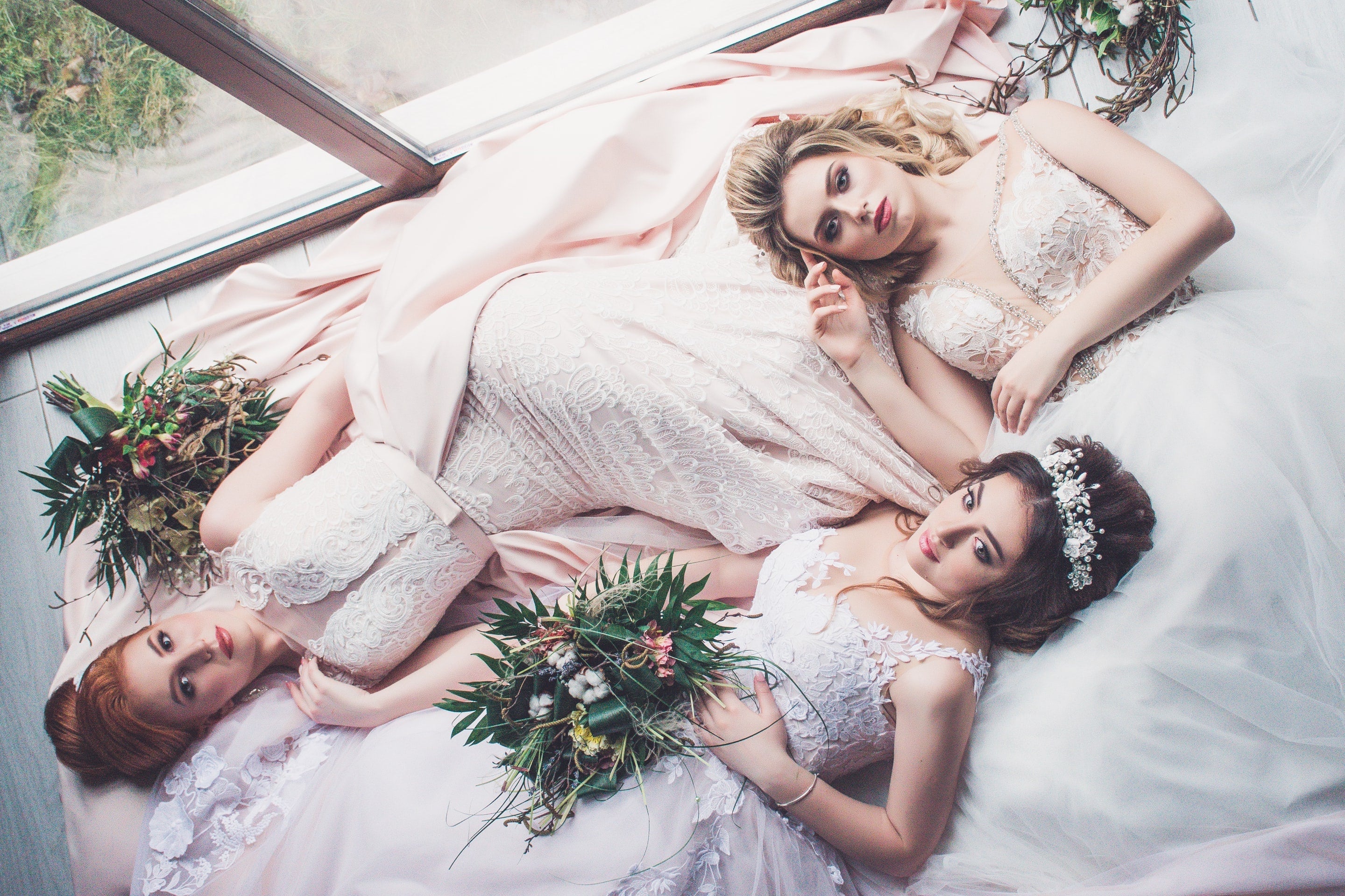 Three brides, blonde, red, and brunette, recline together.